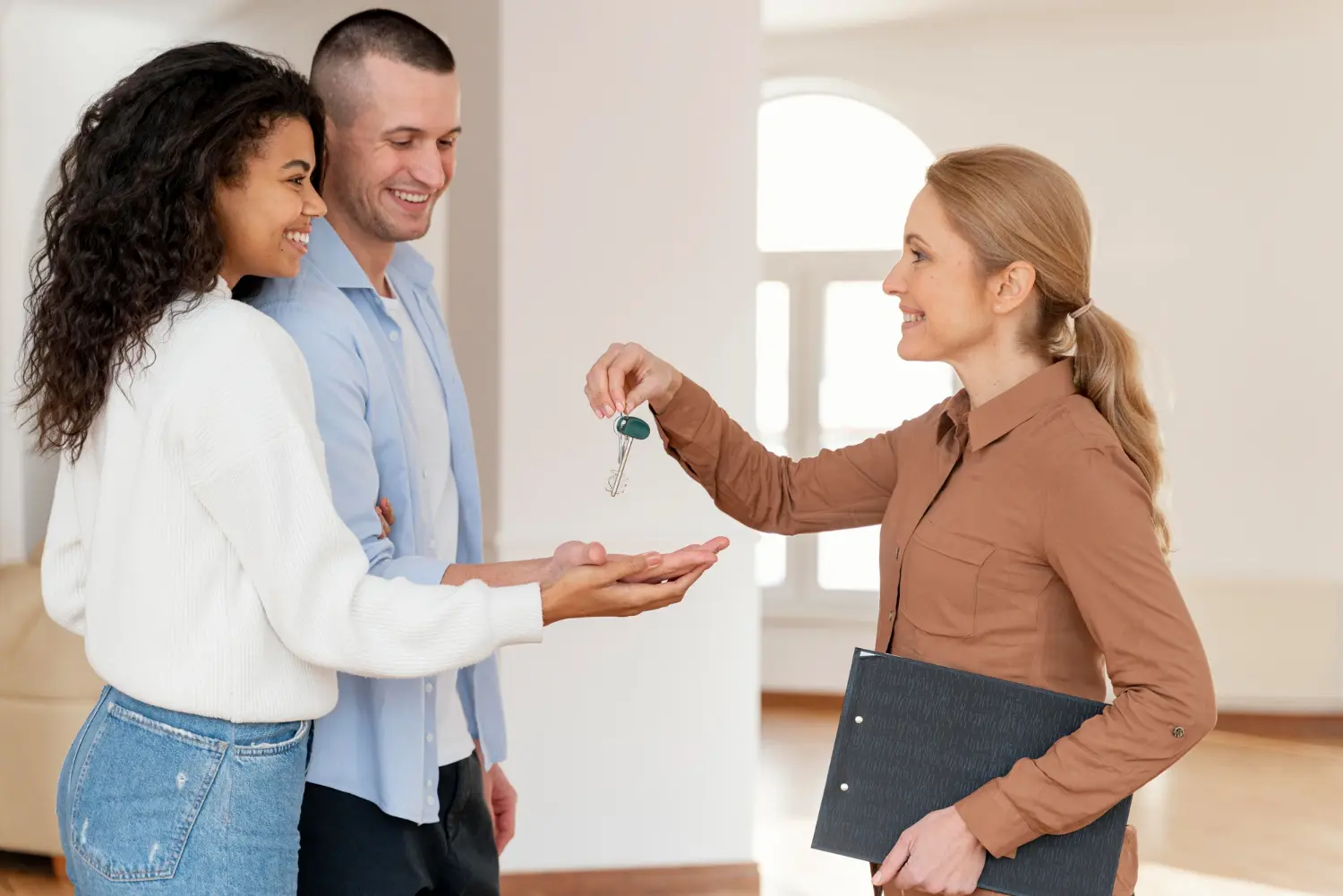 Agente de GAO HOME entregando las llaves a una pareja feliz
